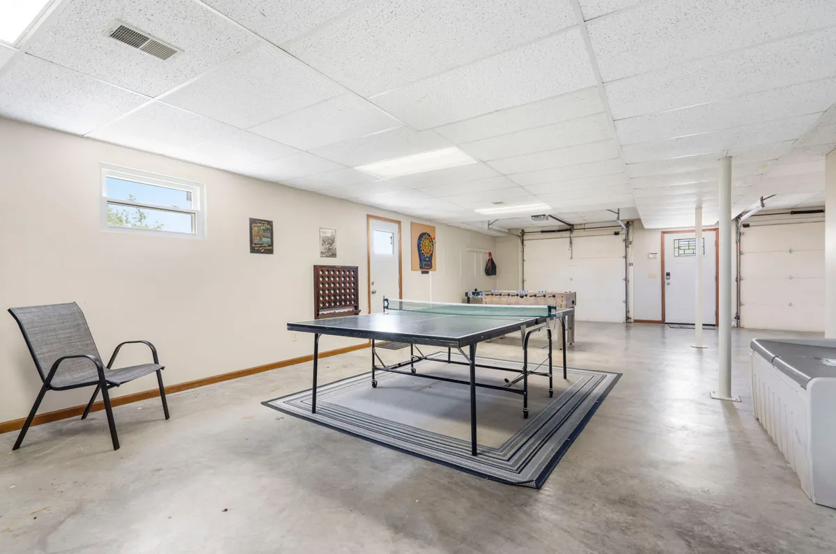 Inside the transformed garage, this image showcases a ping pong table, seating area, garage door, and cheerful wall art. The setup clearly highlights recreational activities and social space, evoking friendly competition and laughter as described in the section.