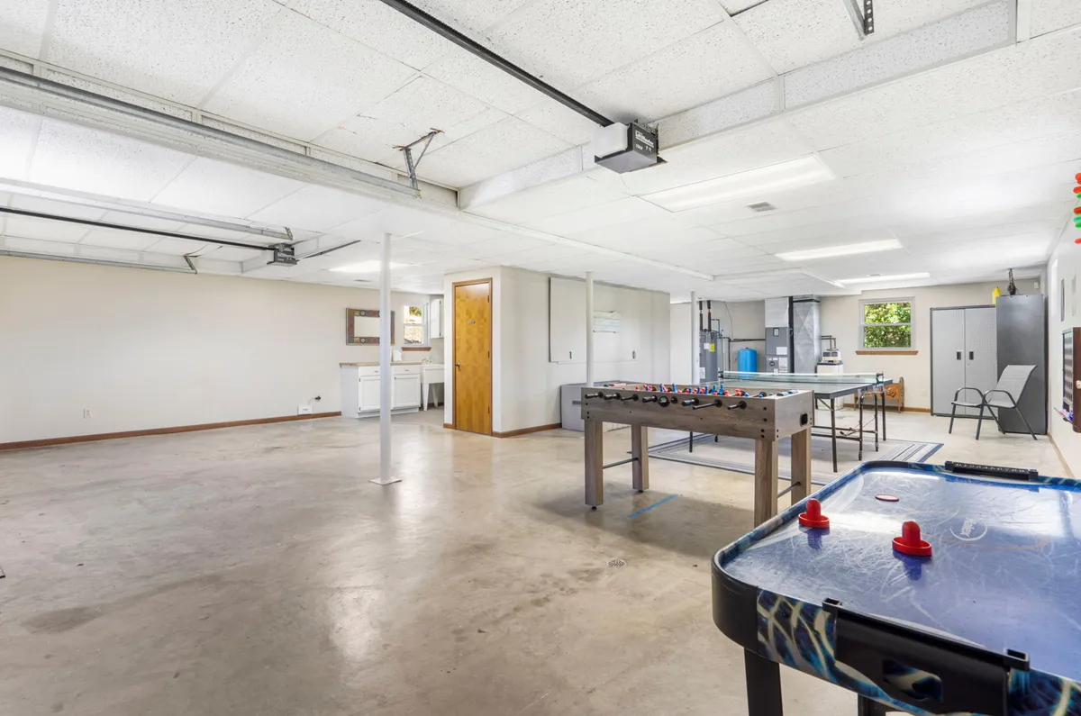 This interior shot reveals a foosball table, an air hockey table, a workbench, and a laundry area—all within the garage. The playful mood and multi-use setup make it clear that this is a dynamic space for both games and casual gatherings.