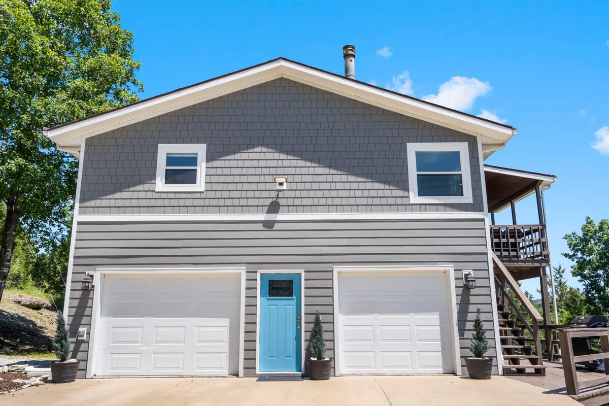 An inviting exterior view focusing on the blue front door, garage doors, and the porch area. This scene sets the stage for welcoming family and friends, and visually references the garage—the home's game and activity hub as featured in the section.