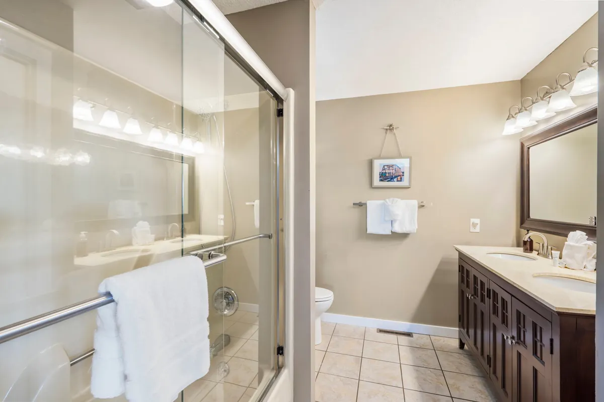 A modern full bathroom with a double vanity, large shower enclosure, and stylish decorative artwork. The calm color palette and thoughtful details make this a soothing space for morning and nighttime routines.