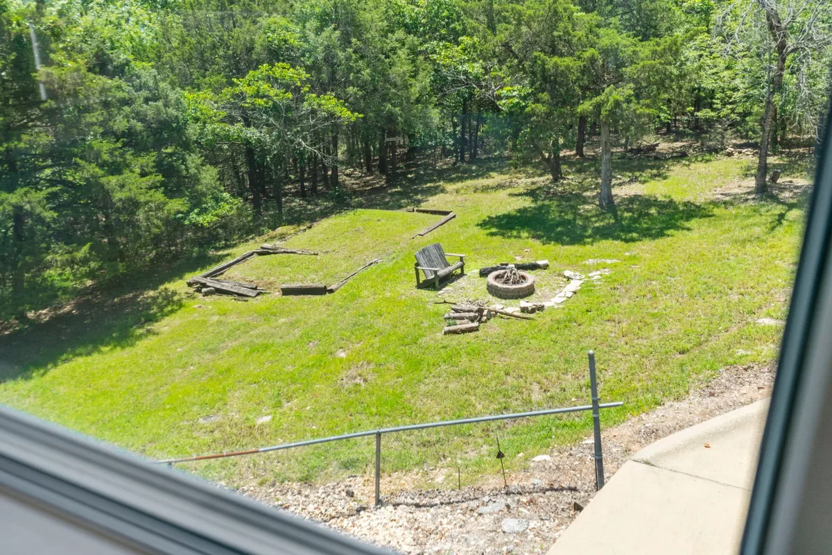 This exterior shot features a fire pit surrounded by Adirondack chairs on a cleared grassy area, inviting guests to gather outdoors. The tranquil setting highlights the opportunity for stargazing, campfire gatherings, and relaxation under the stars—perfect for s'mores and evening stories as described in the section.