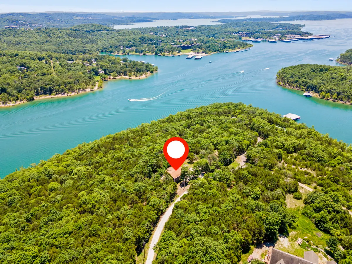 A sweeping view of lush green forest and sparkling blue lake, with a curved road inviting exploration of the lakeshore. The tranquil water and expansive scenery evoke relaxation and adventure in equal measure, hinting at the blend of activity and peace available just steps from the property.
