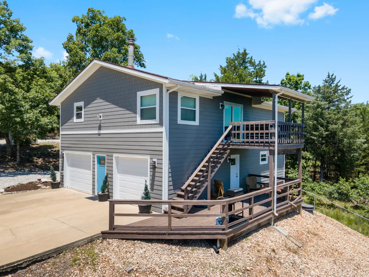 An inviting exterior shot of the house, showcasing the welcoming porch area, the staircase, and the tranquil natural setting that surrounds the home.